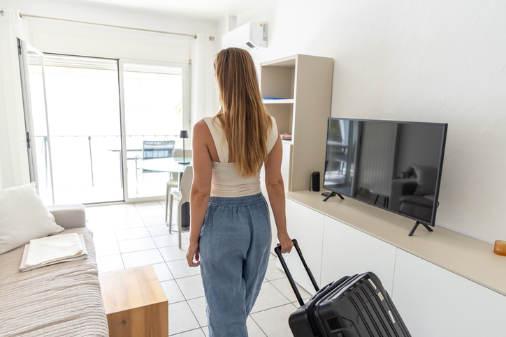 Woman ready to move, holding luggage while planning an apartment search in Lansing, MI